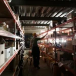 Pekerja gudang mengatur persediaan barang dagangan di rak logam dalam fasilitas penyimpanan